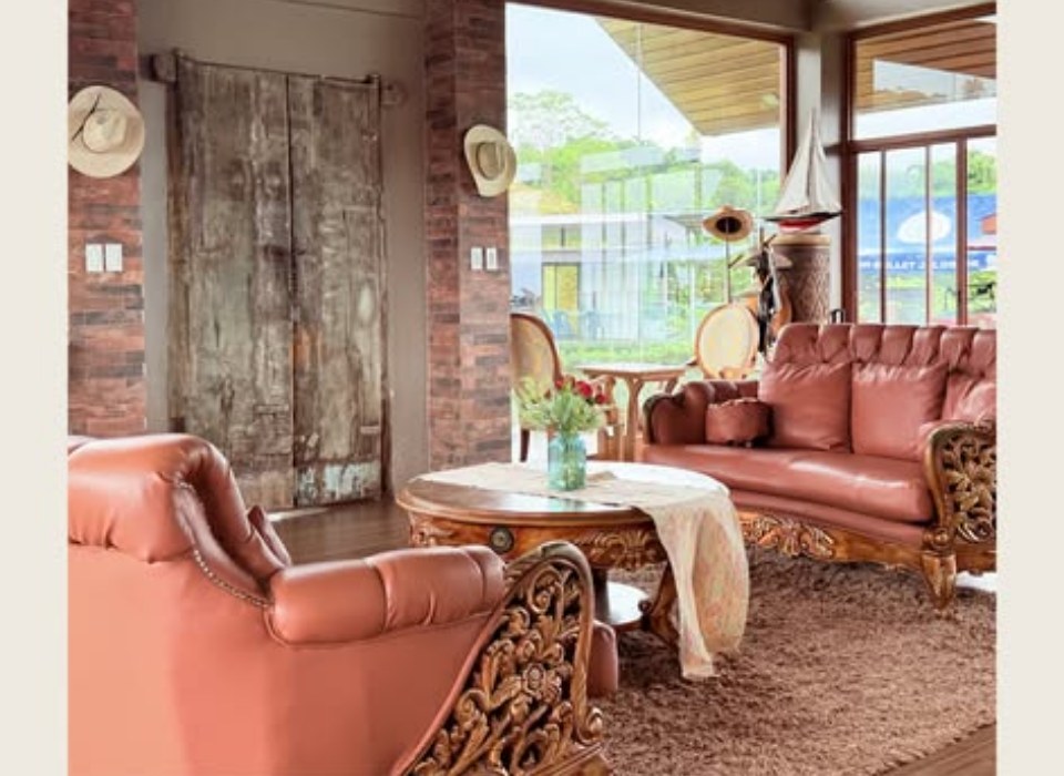 Leather sofas under a warm wood ceiling, floor-to-ceiling glass looking onto the paddocks