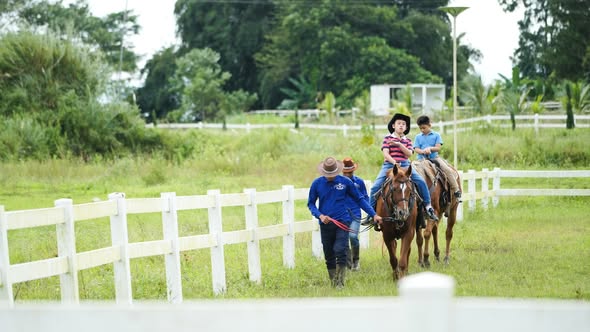 Handlers walking two children on horseback along the rail
